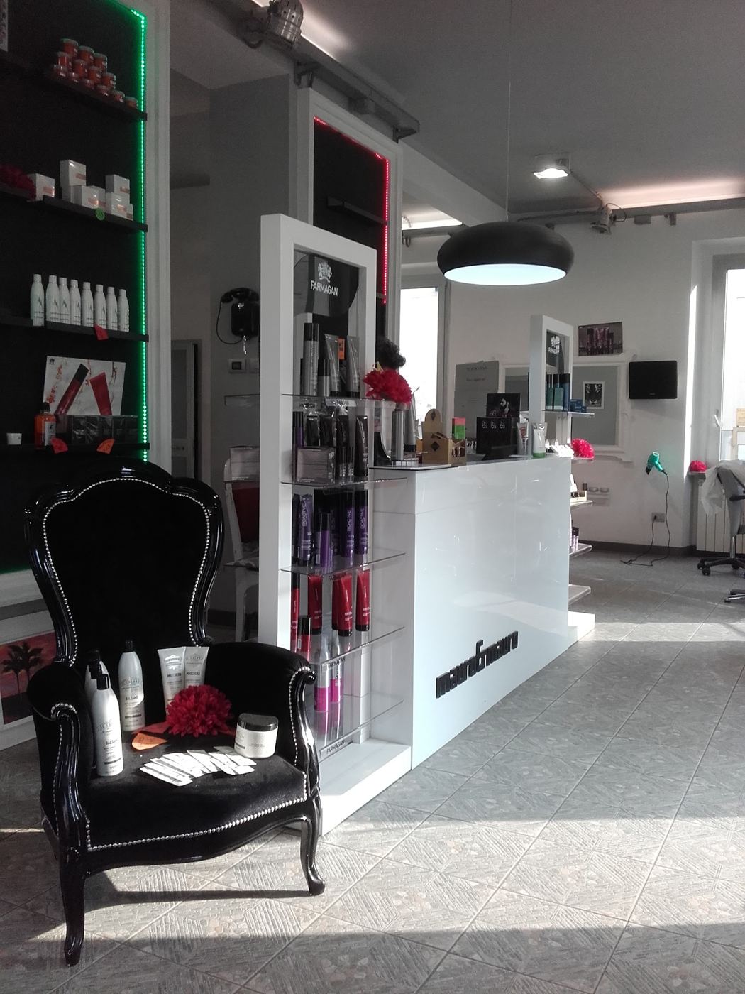 Ingresso del salone Mauro & Mauro: poltrona barocca nera, espositore prodotti e bancone bianco con il logo